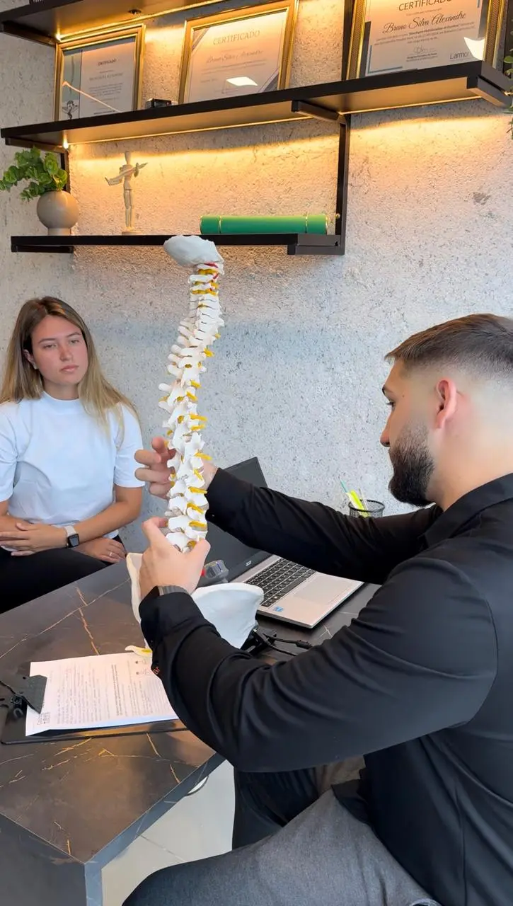 Quiropraxista da Clínica Coluna mais Leve explicando coluna vertebral para paciente em Gravataí-RS